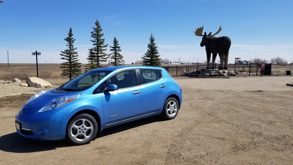 blue EV in front of Mac the Moose in Moose Jaw